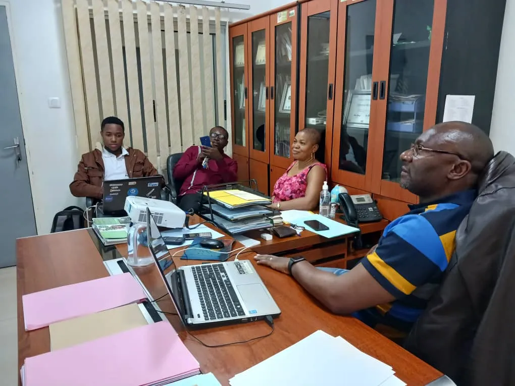 Nsom Emmanuel in a meeting at CHAC with laptops and documents on the table
