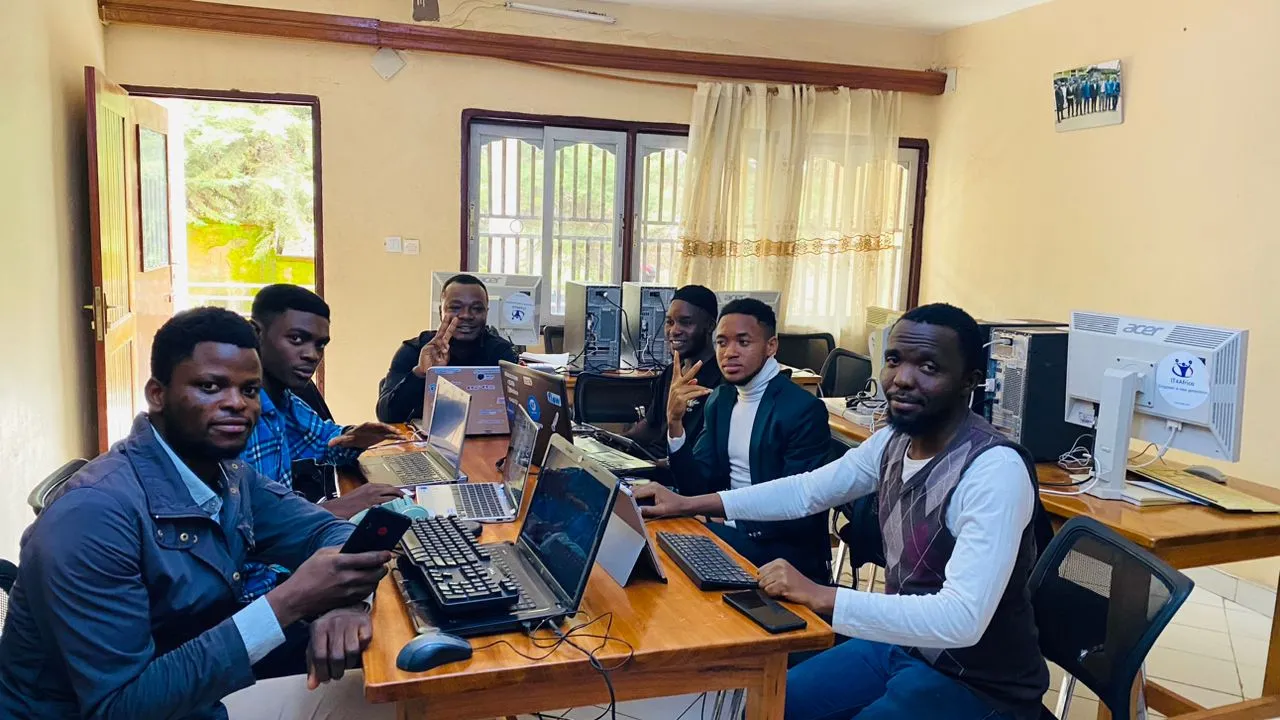 Trainees and Nsom Emmanuel around laptops in a computer room