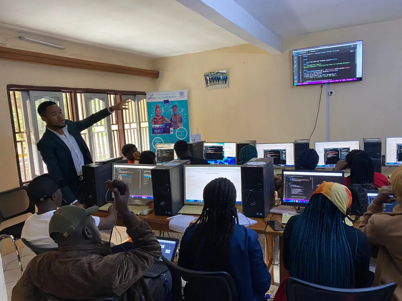 Nsom Emmanuel pointing at a screen while teaching a room of trainees