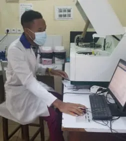 Nsom Emmanuel working at a laboratory analyser and computer