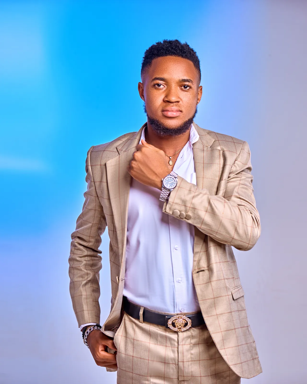 Nsom Emmanuel — beige suit, blue backdrop