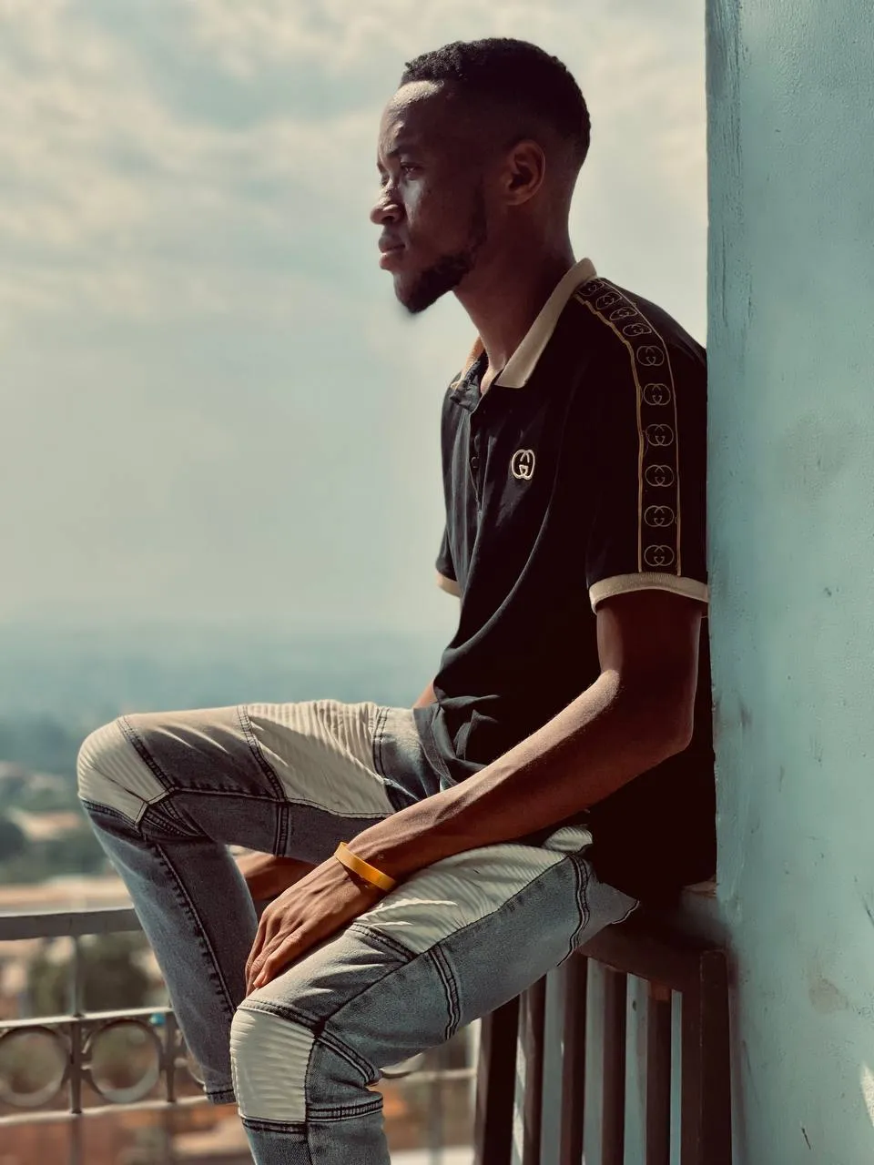 Nsom Emmanuel seated on a balcony ledge looking out over the city
