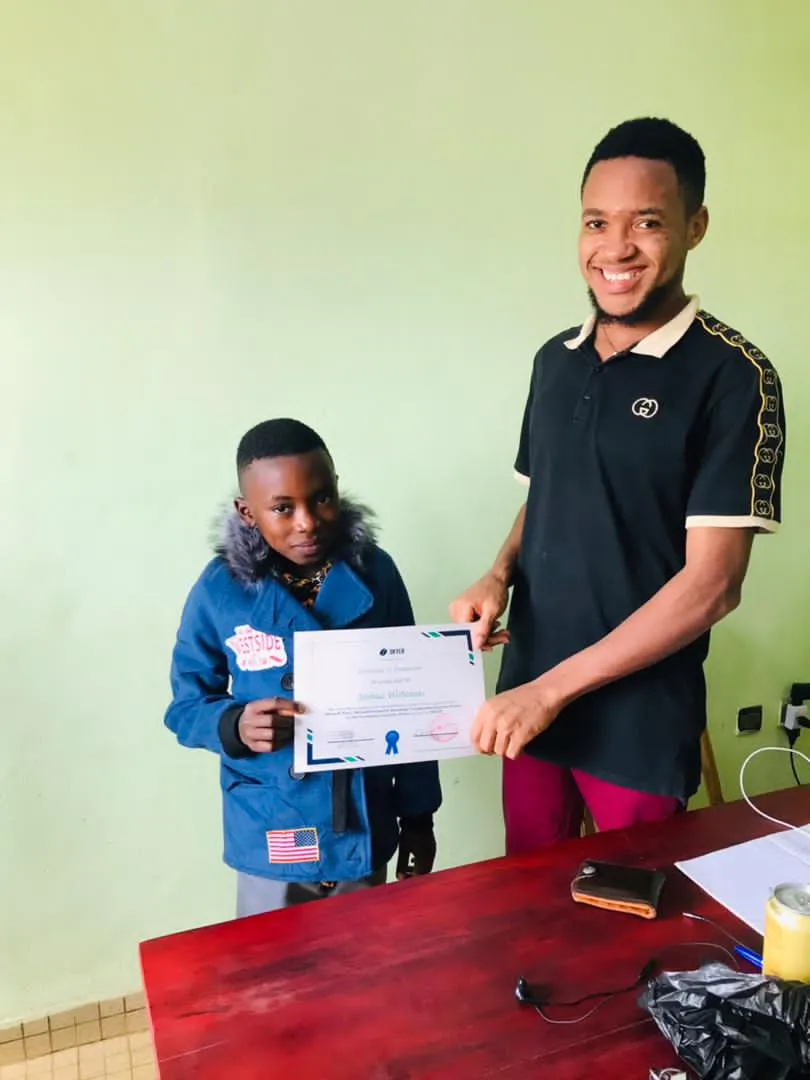 Nsom Emmanuel presenting a certificate to a young trainee