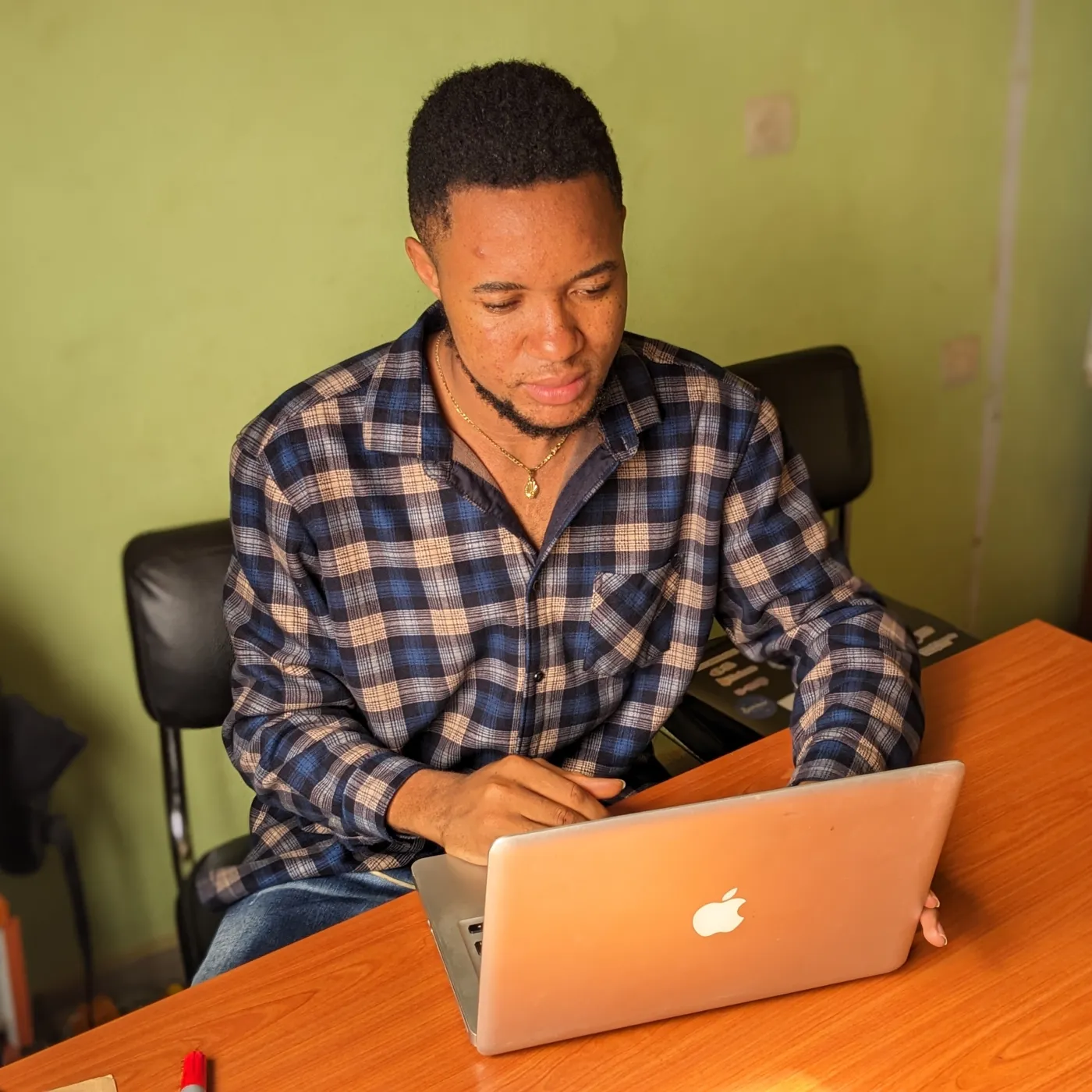 Nsom Emmanuel working on a laptop at a desk